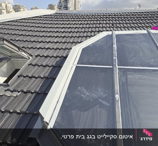גג רעפים עם חלון זכוכית ושמים בהירים